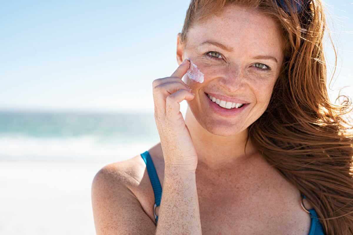 donna con capelli rossi che applica crema