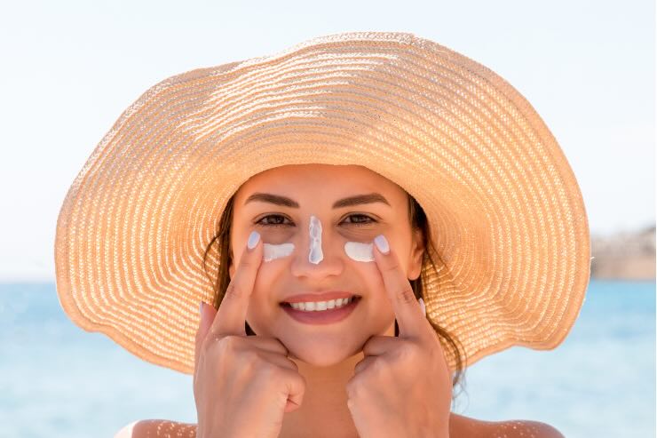 donna che applica crema solare con cappello